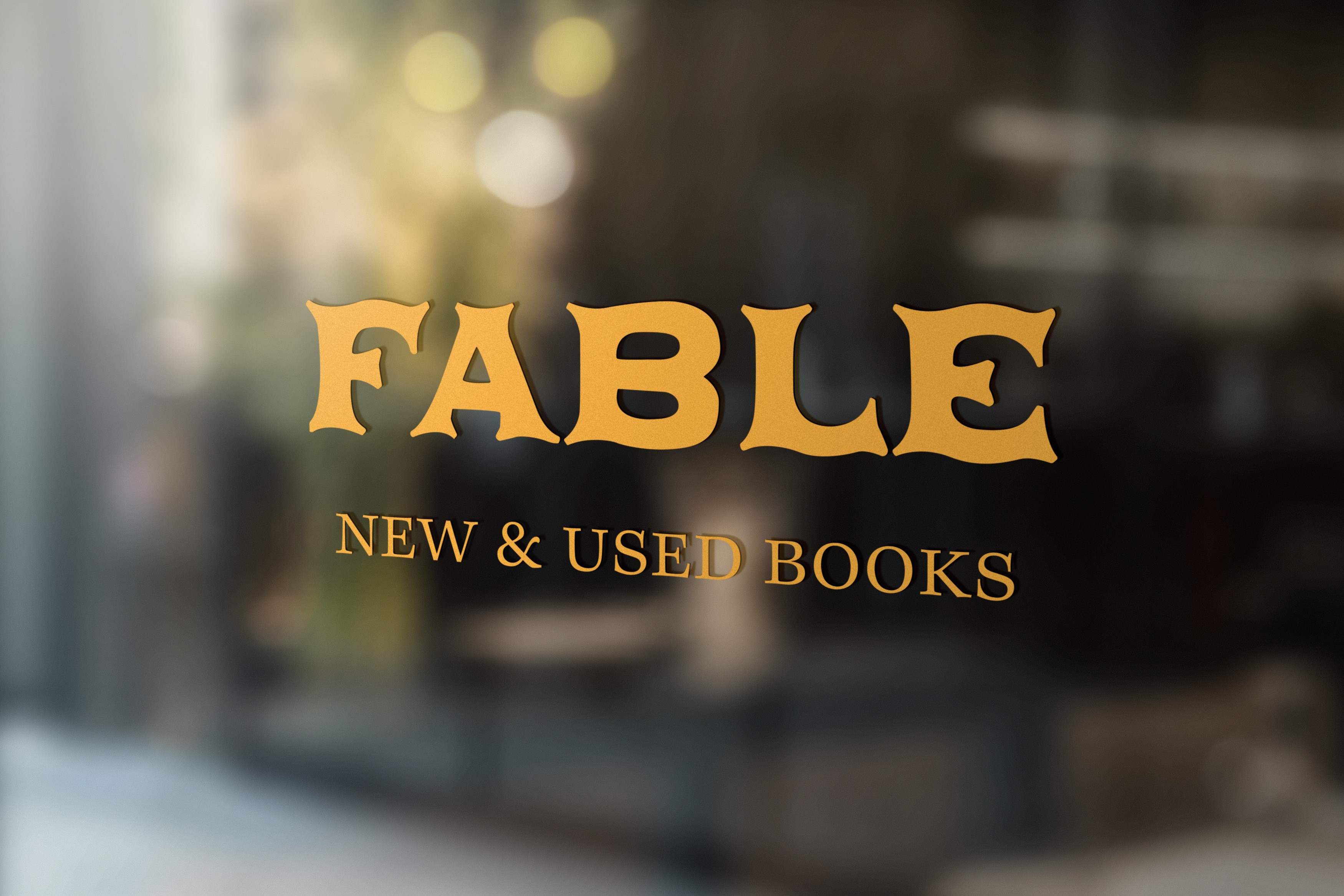 A glass window with signage on it that reads "Fable New and Used Books"